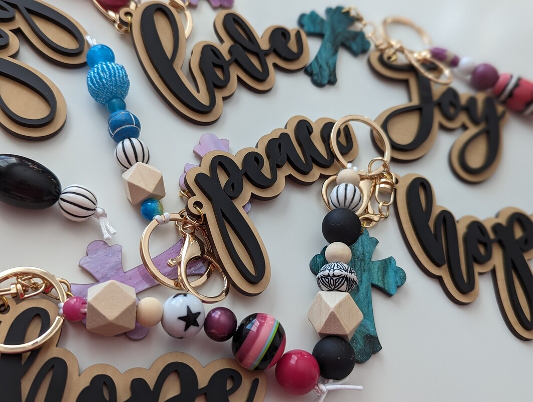 An assortment of Love, Peace, Hope and Joy charms with beaded wristlets and resin crosses
