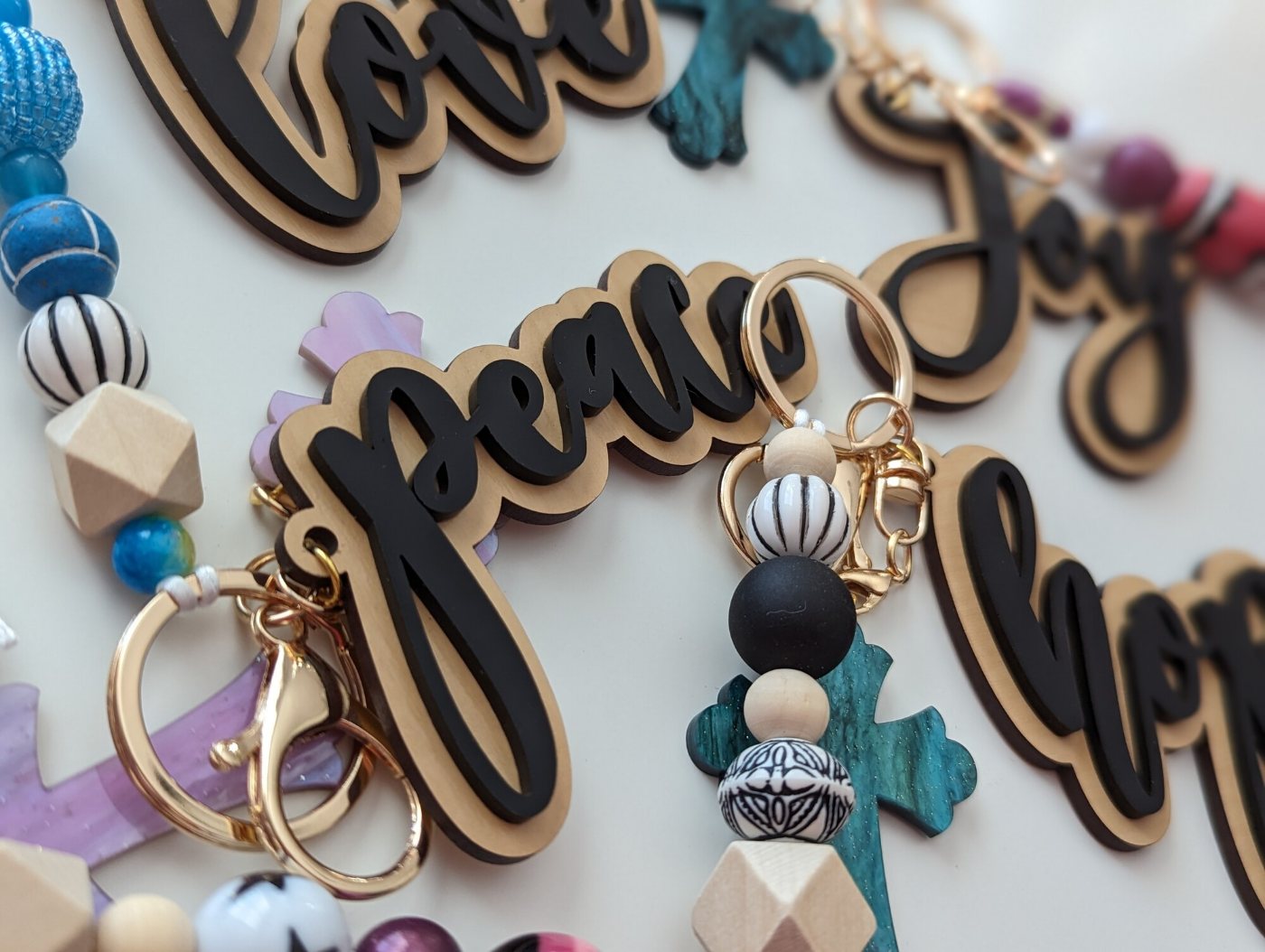 Love, Peace, Hope and Joy script charms in laser-cut wood and black acrylic, strung with colorful beads and gold clasps